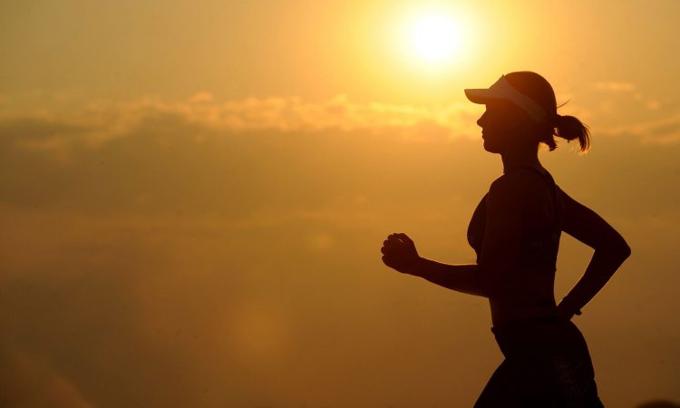 Woman running in front of a sunset