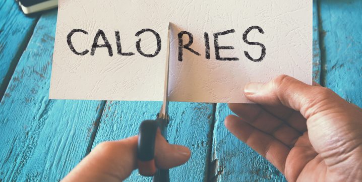 Feuille de papier écrit "Calories" qui se fait couper par des ciseaux
