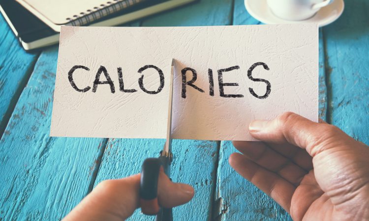 Feuille de papier écrit "Calories" qui se fait couper par des ciseaux