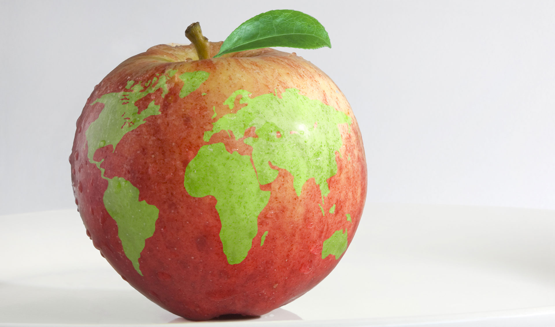 A red apple with green spots that represent the continents of the earth