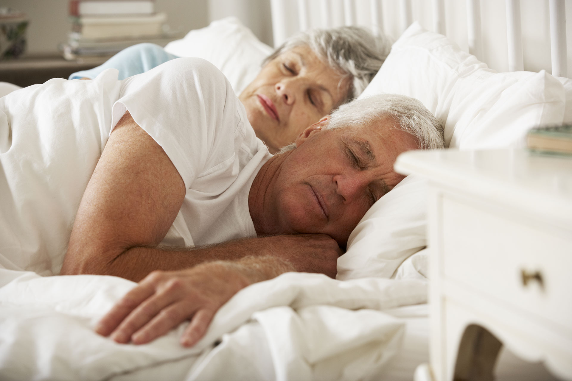 Elderly couple sleeping in a bed