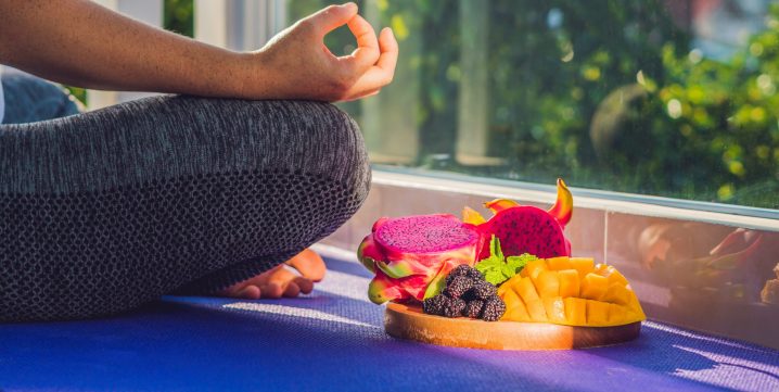 femme en position de yoga avec une assiette de fruits