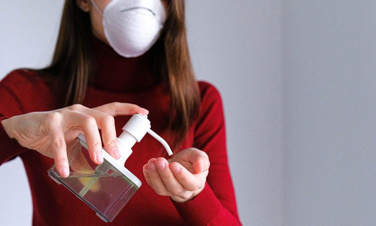 Femme portant un masque et utilisant un désinfectant pour les mains.