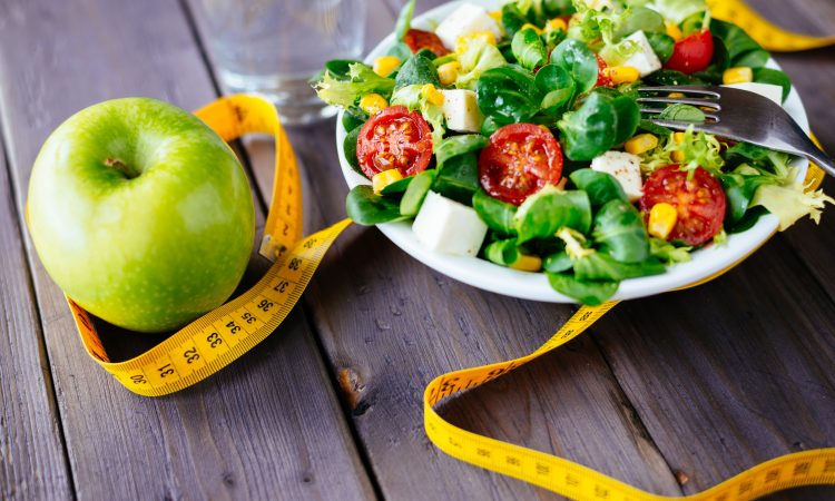 assiette de salade avec une pomme et un ruban à mesurer