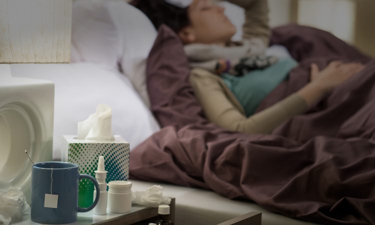 femme couchée dans son lit avec des médicaments contre le rhume et la grippe
