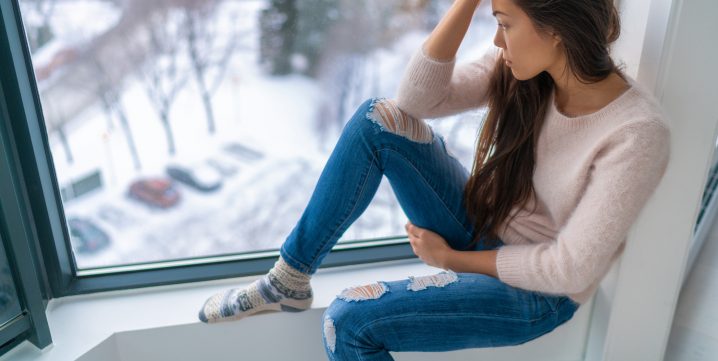 jeune femme déprimée regardant la neige par la fenêtre